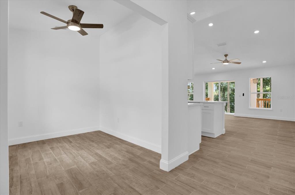 A bright dining area with wood-look tile floors and a ceiling fan opens to a kitchen — 300 CHEROKEE AVENUE, ORANGE CITY, FL