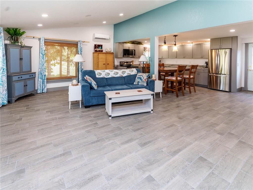 An open-concept living room and kitchen feature gray wood-look tile flooring and blue walls — 4910 LIMESTONE DRIVE, PORT RICHEY, FL
