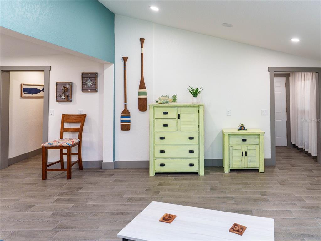 A room with wood-look tile flooring, light green furniture, and nautical wall decor — 4910 LIMESTONE DRIVE, PORT RICHEY, FL