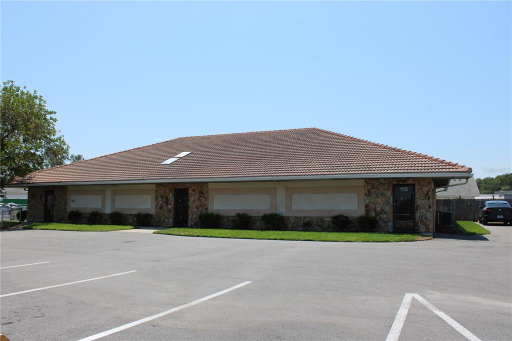 A single-story commercial building with a tiled roof, stone facade, and a paved parking lot — 1158 ALTERNATE HWY 19 UNIT 1, HOLIDAY, FL