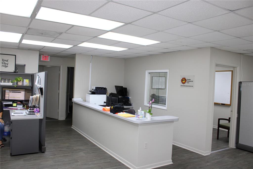 An office reception area features a long counter, gray flooring, and a drop ceiling — 1158 ALTERNATE HWY 19 UNIT 1, HOLIDAY, FL