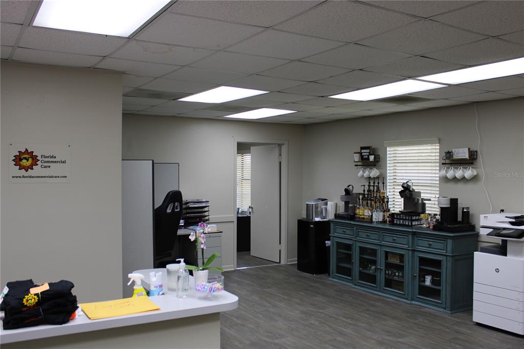 An office interior features a reception desk, a coffee station, and a doorway to another room — 1158 ALTERNATE HWY 19 UNIT 1, HOLIDAY, FL