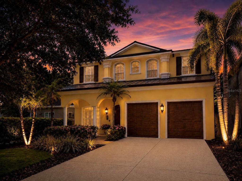 A two-story yellow house with a two-car garage and arched windows at sunset — 5916 6TH STREET, TAMPA, FL