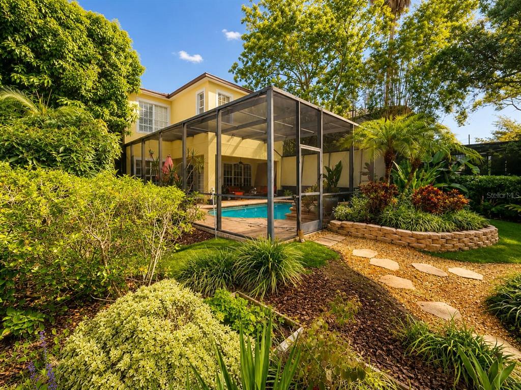 A yellow two-story house features a screened-in pool and a landscaped backyard with stone paths — 5916 6TH STREET, TAMPA, FL