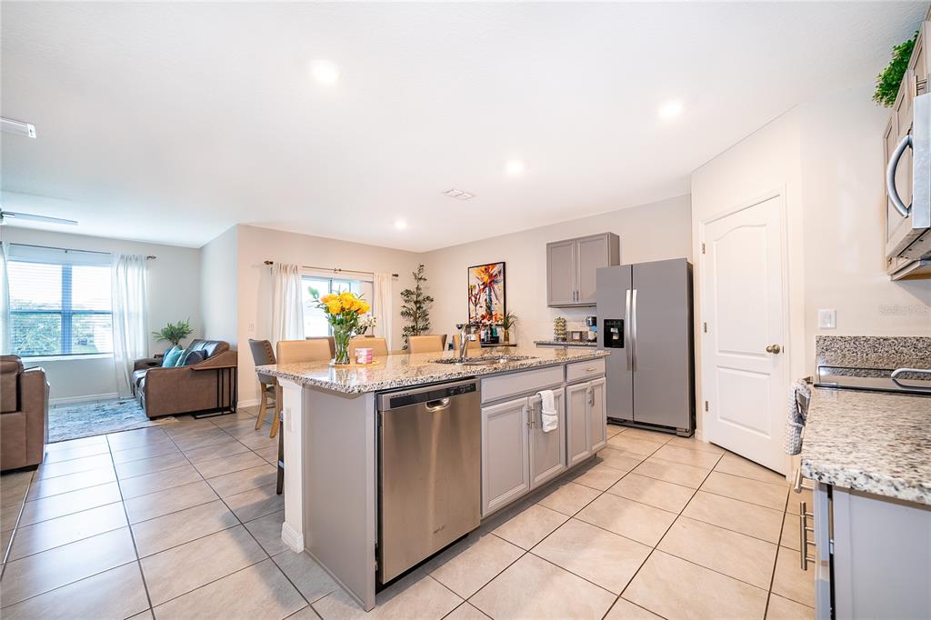 A kitchen with gray cabinets, granite countertops, and a stainless steel dishwasher and refrigerator — 1933 BELLKNOLL LANE, KISSIMMEE, FL