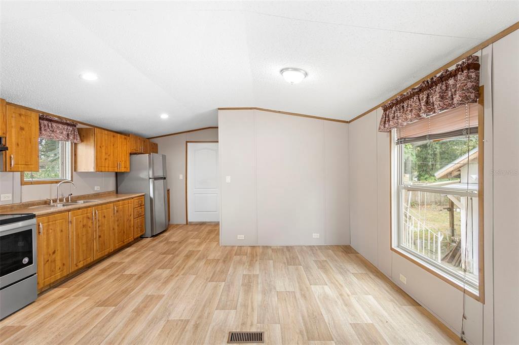 A kitchen with wood cabinets, stainless steel appliances, and light wood-look flooring — 2530 CRESAP STREET, LAKELAND, FL