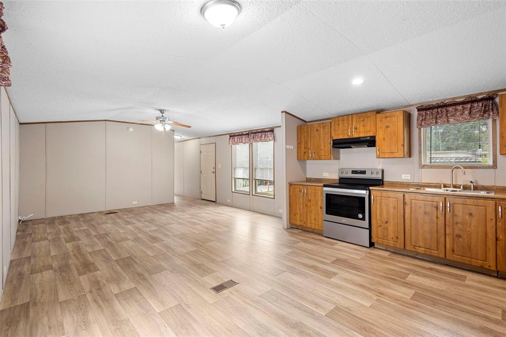 An open-concept kitchen and living area with wood-look flooring and light-colored paneled walls — 2530 CRESAP STREET, LAKELAND, FL