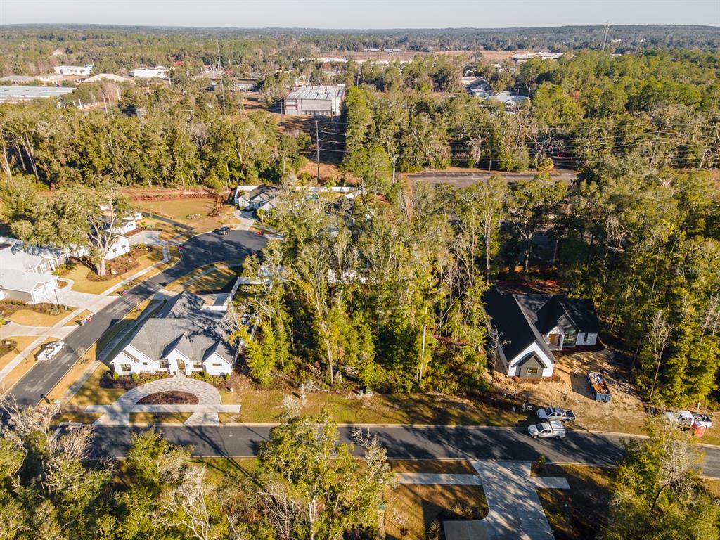 An aerial view shows two houses surrounded by trees near a paved road and neighborhood — 14110 SW 7TH PLACE, NEWBERRY, FL