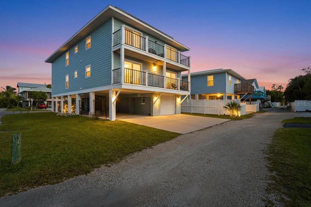 A three-story blue house on stilts with two stacked balconies and a concrete driveway — 2518 AVENUE B, BRADENTON BEACH, FL