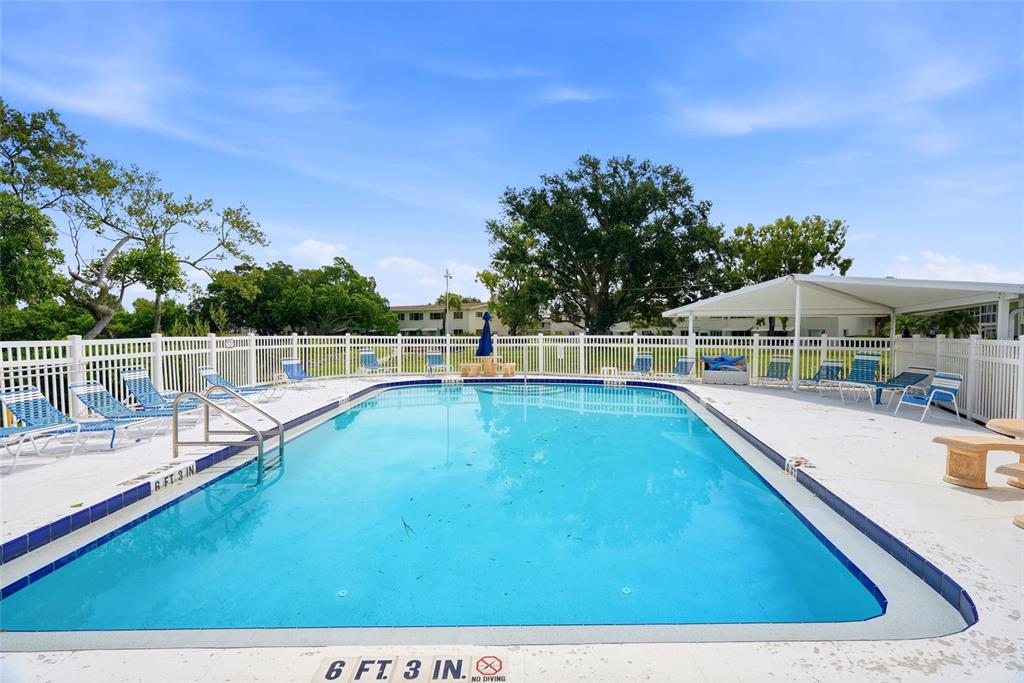 A rectangular swimming pool is surrounded by a white fence and several lounge chairs — 4570 OVERLOOK DRIVE NE UNIT 175, ST PETERSBURG, FL