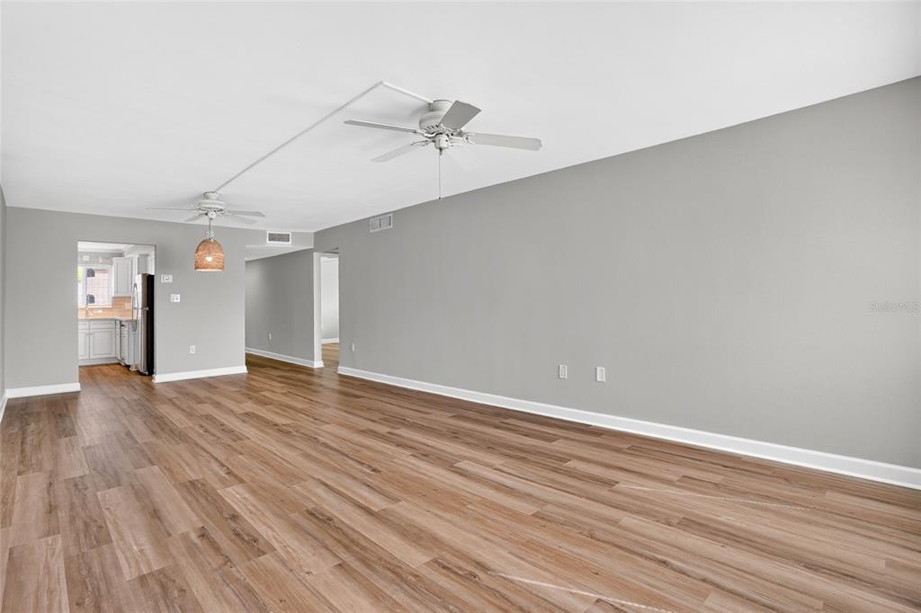 An empty living room features light gray walls, wood-look flooring, and two ceiling fans — 4570 OVERLOOK DRIVE NE UNIT 175, ST PETERSBURG, FL