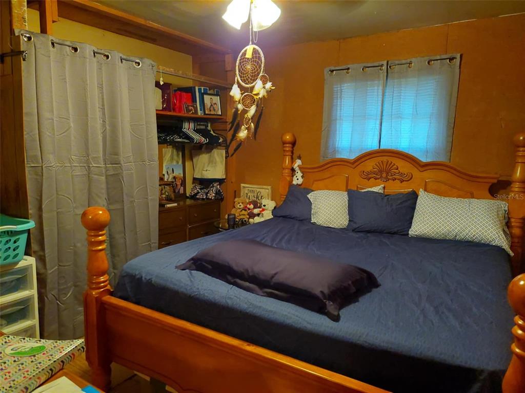 A bedroom features a large wooden bed, a closet with a curtain, and a dreamcatcher — 14016 N. HWY 301, THONOTOSASSA, FL