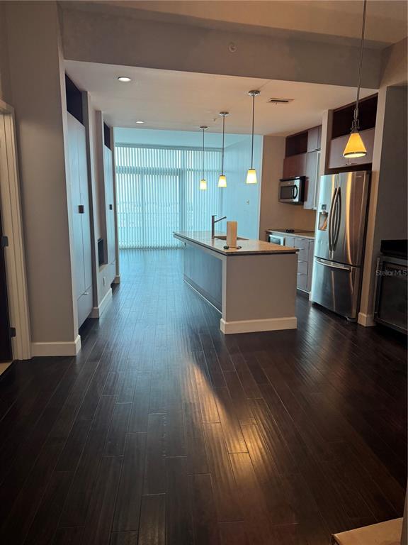 A modern kitchen features a central island, stainless steel appliances, and dark hardwood flooring — 912 CHANNELSIDE DRIVE UNIT 2803, TAMPA, FL
