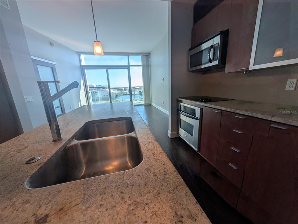 A kitchen features a granite island with a double sink, dark cabinetry, and balcony views — 912 CHANNELSIDE DRIVE UNIT 2803, TAMPA, FL