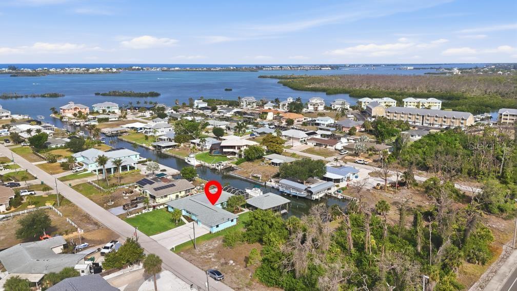 An aerial view shows a light blue house with a red location pin on a canal — 1980 MICHIGAN AVENUE, ENGLEWOOD, FL