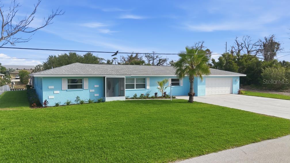 A single-story light blue house with a white garage and a front lawn — 1980 MICHIGAN AVENUE, ENGLEWOOD, FL