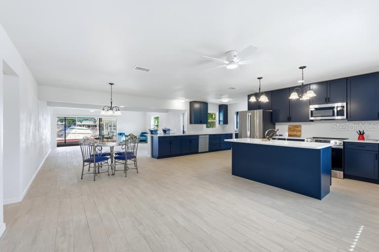 A spacious kitchen features navy blue cabinetry, a central island, and light-colored tile flooring — 1980 MICHIGAN AVENUE, ENGLEWOOD, FL