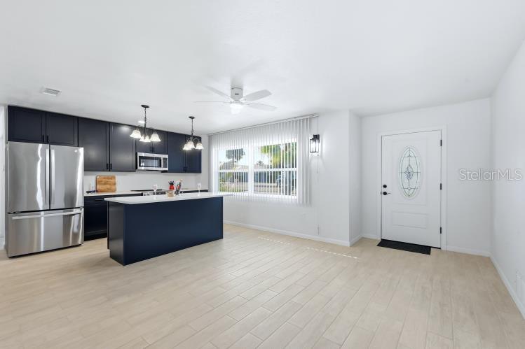 A kitchen with dark cabinets, a central island, and stainless steel appliances opens to an entryway — 1980 MICHIGAN AVENUE, ENGLEWOOD, FL