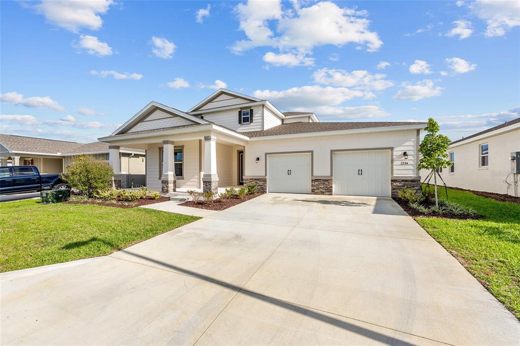 A single-story suburban house with a two-car garage, stone accents, and a covered front porch — 7234 SW 58TH PLACE ROAD, OCALA, FL