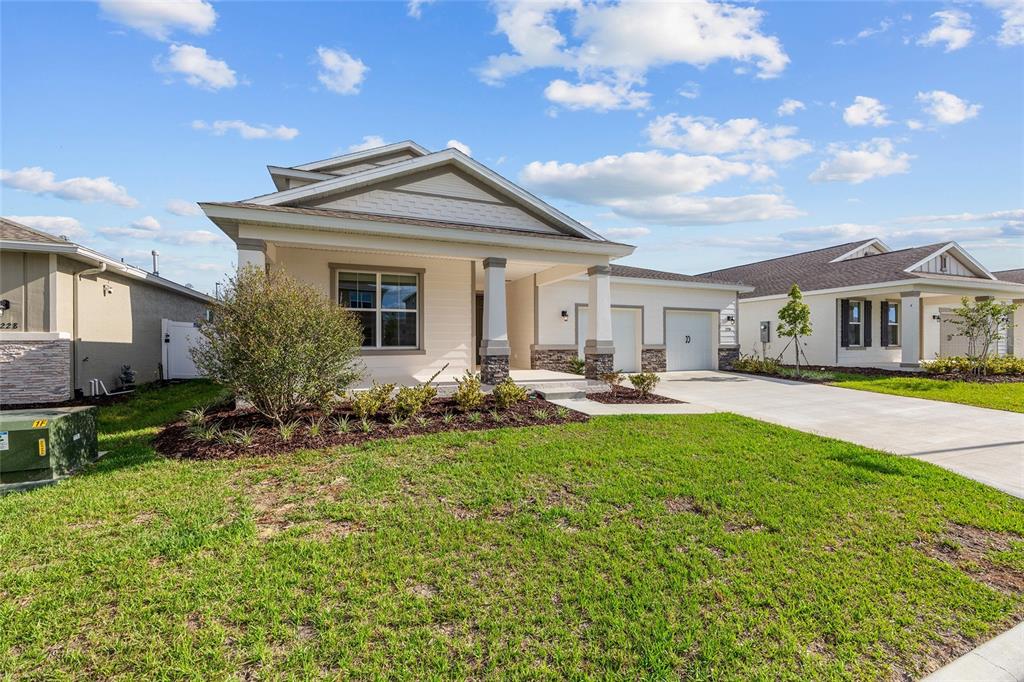 A single-story suburban house features a front porch, a two-car garage, and landscaped lawn — 7234 SW 58TH PLACE ROAD, OCALA, FL