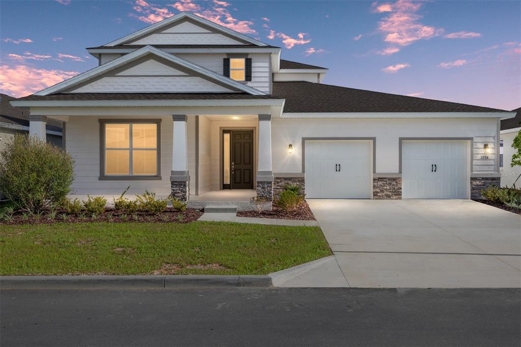A two-story house with white siding, a stone base, and a two-car garage — 7234 SW 58TH PLACE ROAD, OCALA, FL