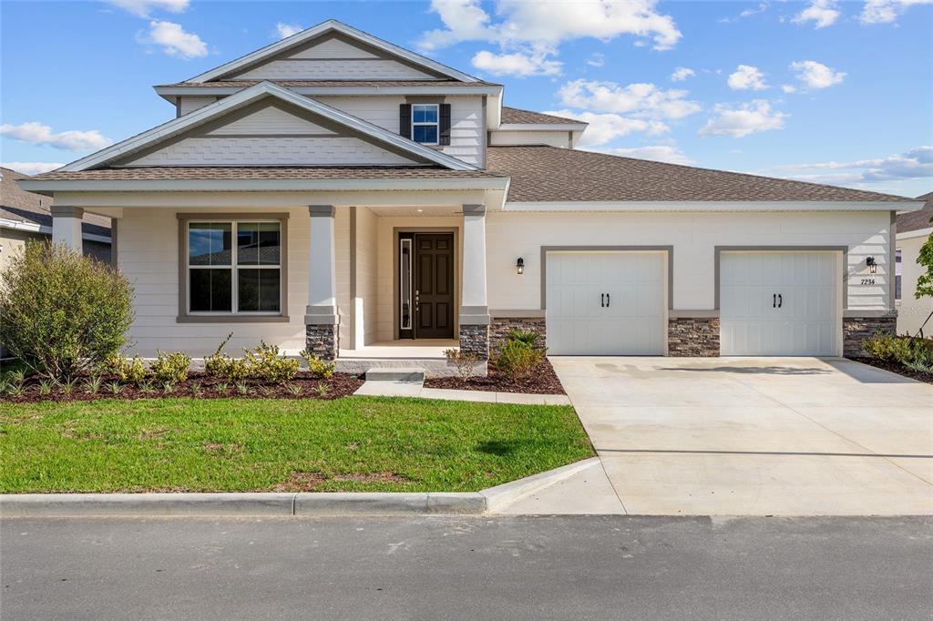 A two-story house with white siding, a stone base, and a two-car garage — 7234 SW 58TH PLACE ROAD, OCALA, FL