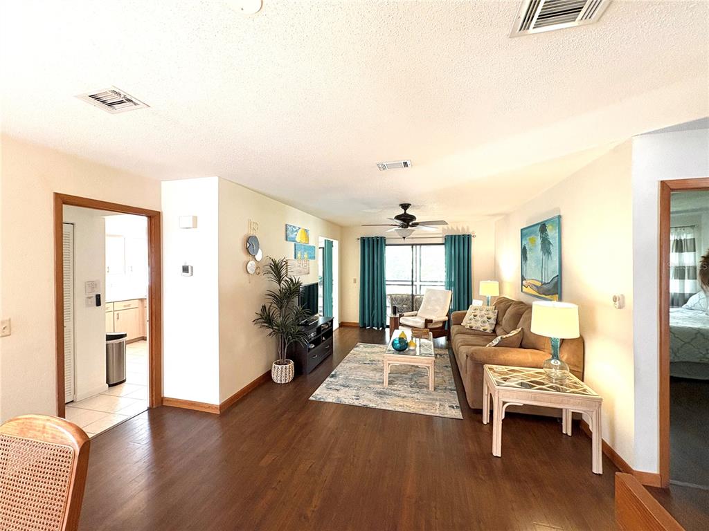 A living room with wood flooring, a brown sofa, and a glass-topped coffee table — 10 OAKMONT COURT UNIT 10, PALM COAST, FL
