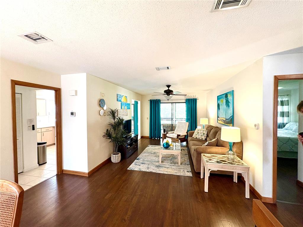 A living room with dark wood floors, a beige sofa, and blue curtains — 10 OAKMONT COURT UNIT 10, PALM COAST, FL