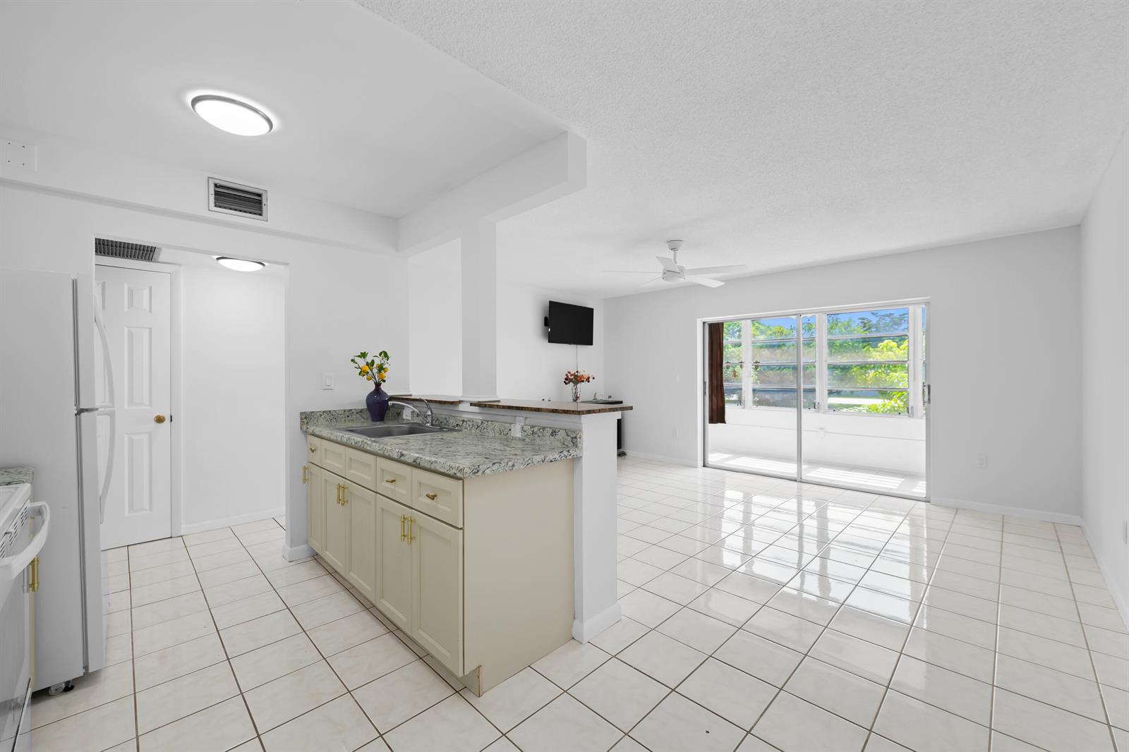A kitchen with granite countertops and a breakfast bar opens into a tiled living area — 5190 E Sabal Palm Boulevard # 209, Tamarac FL 33319, TAMARAC, FL