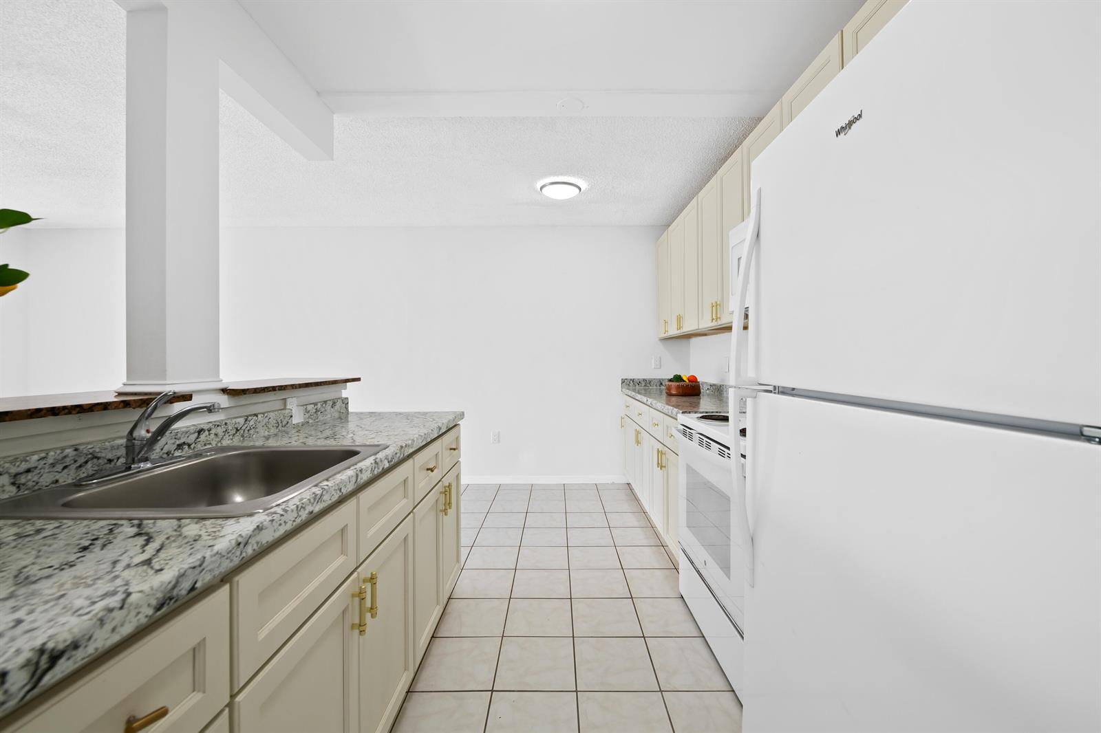 A kitchen features white cabinets, granite countertops, a stainless steel sink, and white appliances — 5190 E Sabal Palm Boulevard # 209, Tamarac FL 33319, TAMARAC, FL