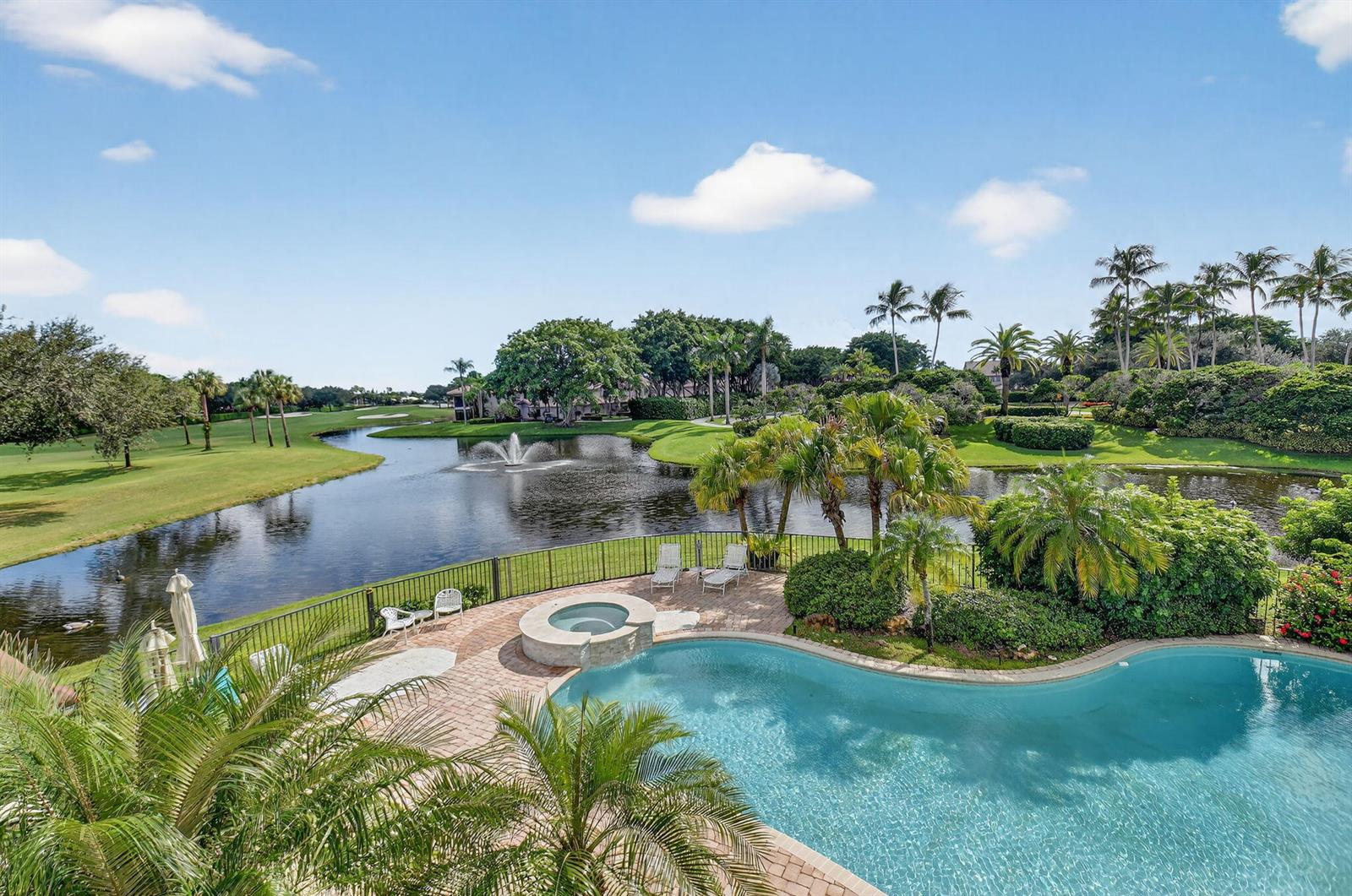 An elevated view of a backyard pool, hot tub, and patio overlooking a golf course pond — 16670 Senterra Drive, Delray Beach FL 33484, DELRAY BEACH, FL