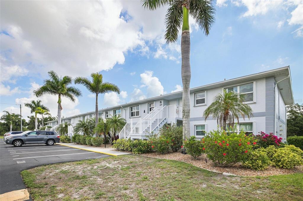 A two-story apartment building with white stucco siding, palm trees, and a parking lot — 26485 RAMPART BOULEVARD UNIT A27, PUNTA GORDA, FL
