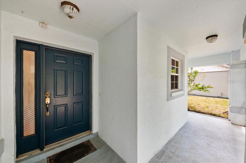 A dark blue front door with a side window sits under a covered entryway — 5003 72ND STREET E, BRADENTON, FL