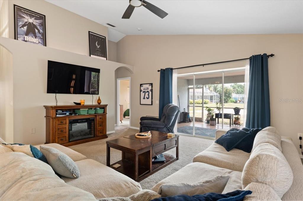 A living room features a television, a wooden media console, and a sliding glass door — 5003 72ND STREET E, BRADENTON, FL