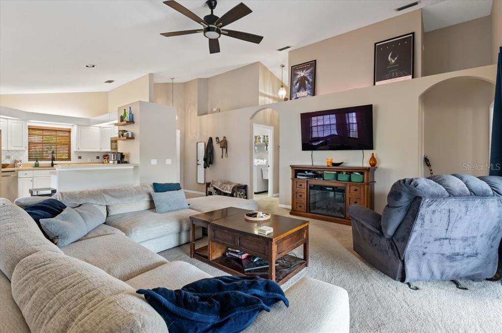A living room features a sectional sofa, a television above a fireplace, and an open kitchen — 5003 72ND STREET E, BRADENTON, FL