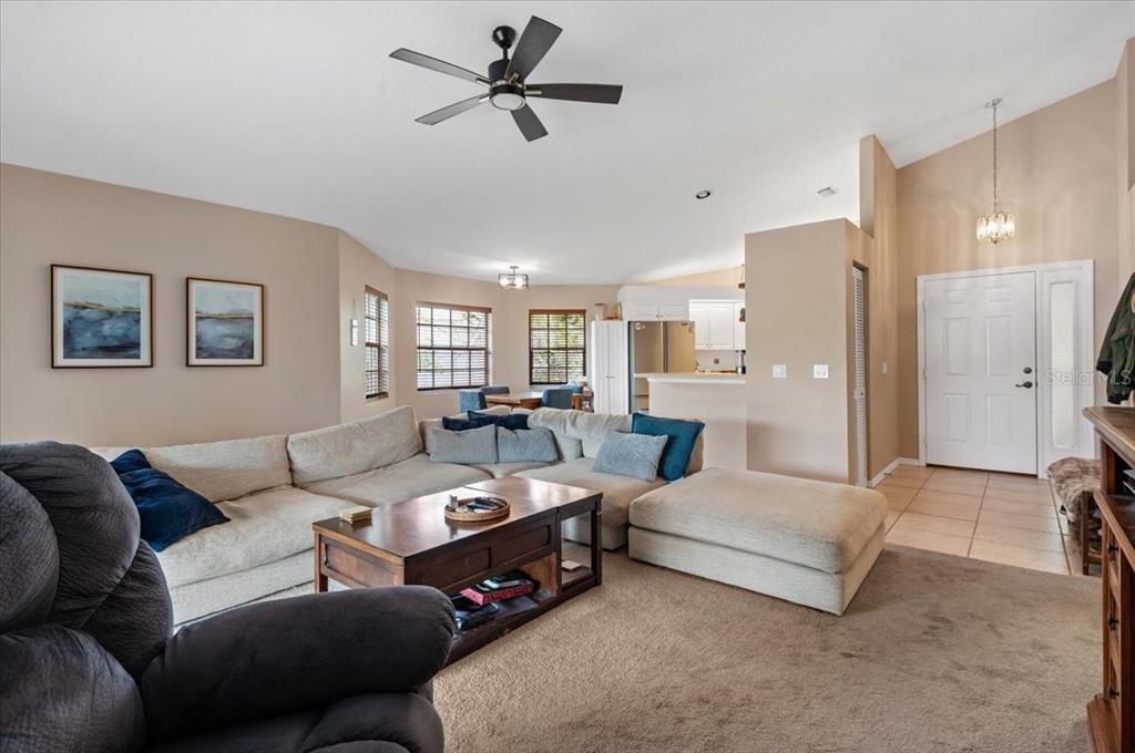 A living room with a large sectional sofa, coffee table, and an adjacent kitchen area — 5003 72ND STREET E, BRADENTON, FL