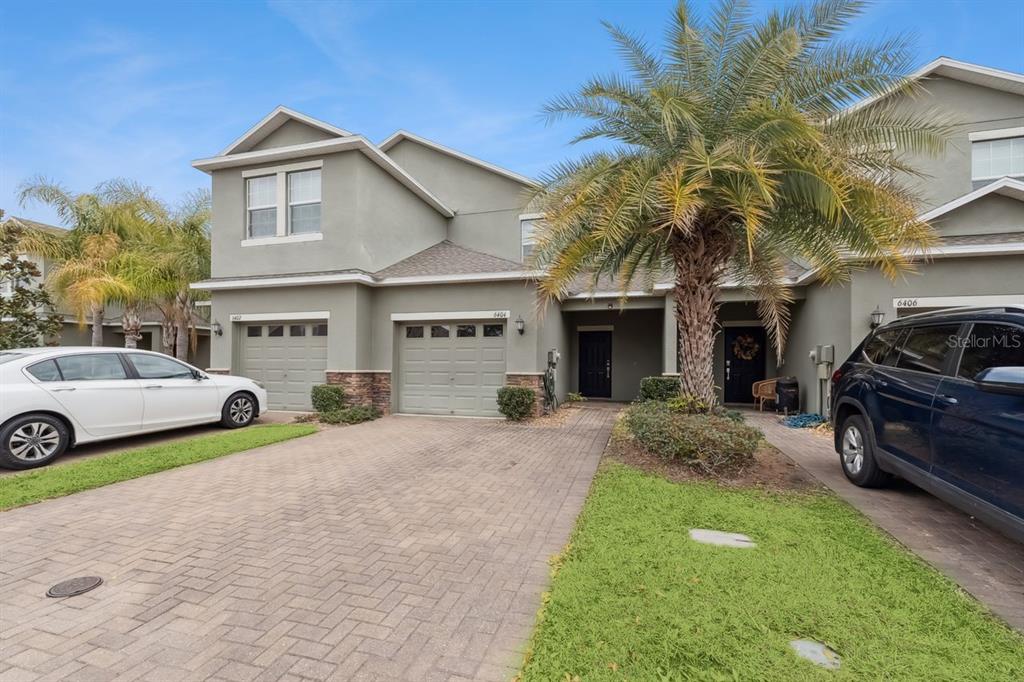 A two-story townhouse exterior with a paved driveway, palm tree, and two parked cars — 6404 TORRINGTON CIRCLE, LAKELAND, FL