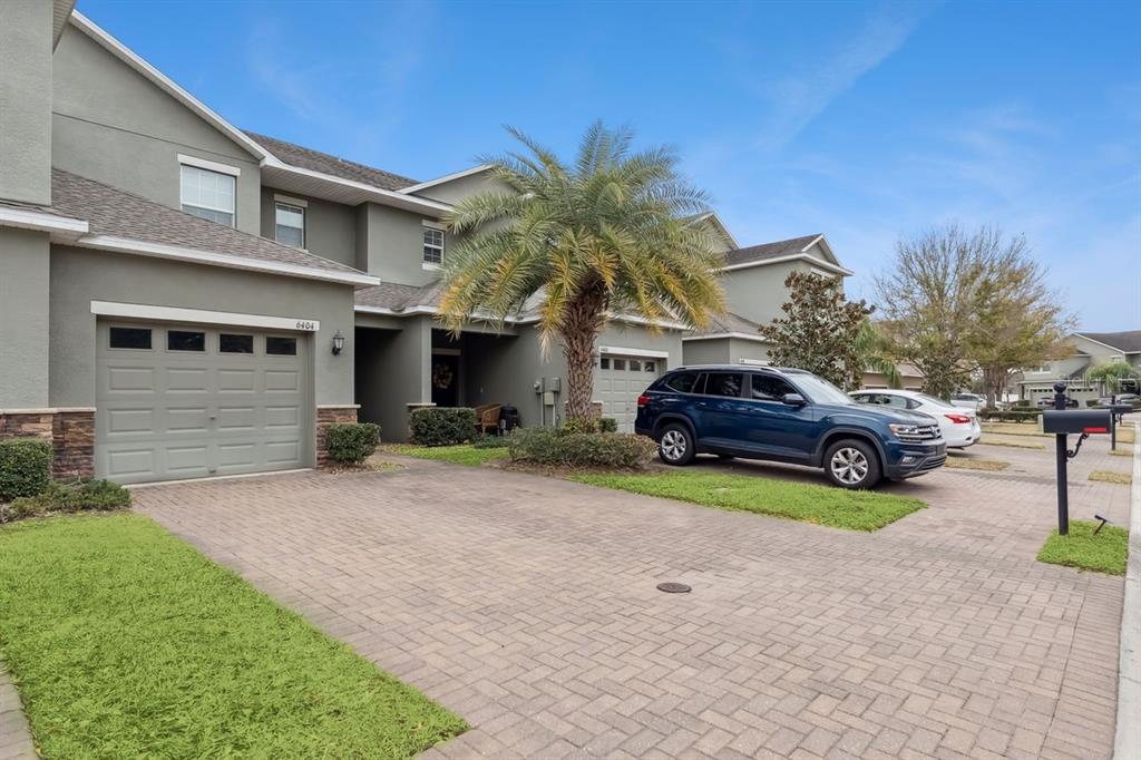 A two-story townhouse with a paved driveway, a garage, and a palm tree in front — 6404 TORRINGTON CIRCLE, LAKELAND, FL