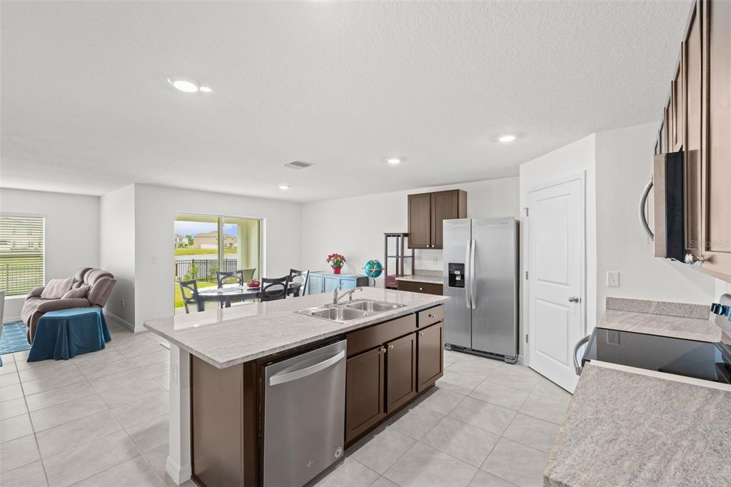A kitchen with dark wood cabinets, granite countertops, a central island, and stainless steel appliances — 12210 KINGSLEY TRAIL, PARRISH, FL