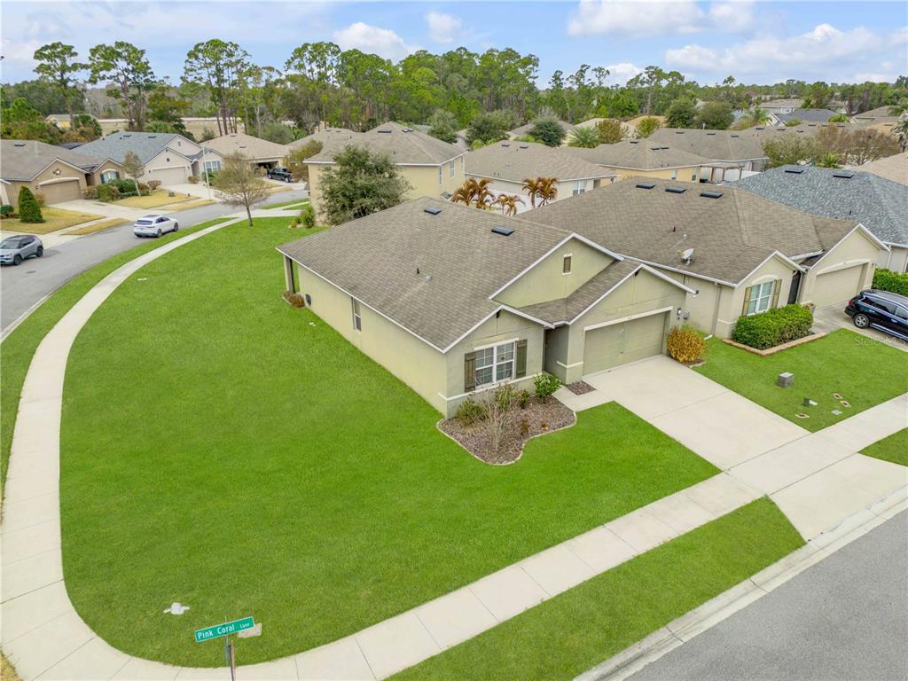 An aerial view of a single-story suburban house with a large corner lawn — 402 PINK CORAL LANE, NEW SMYRNA BEACH, FL