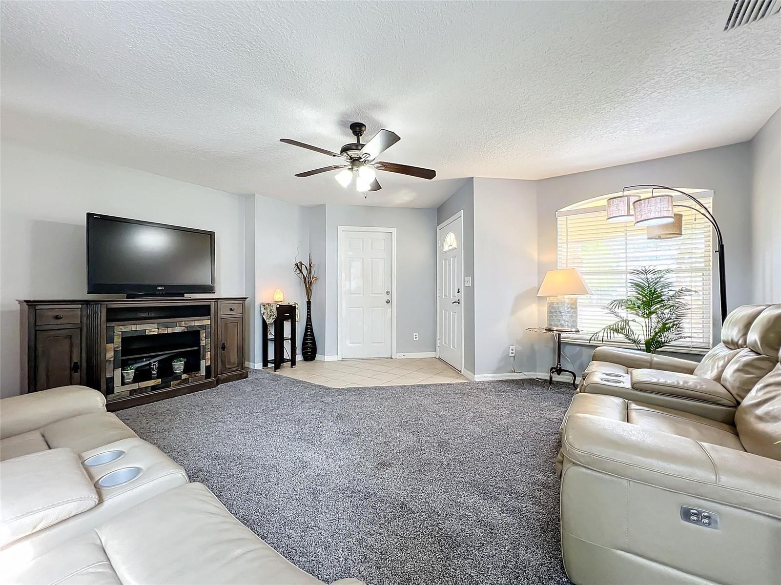 A living room features gray carpet, a television console, two leather sofas, and two doors — 2560 Franklin Avenue, Winter Park FL 32789, WINTER PARK, FL