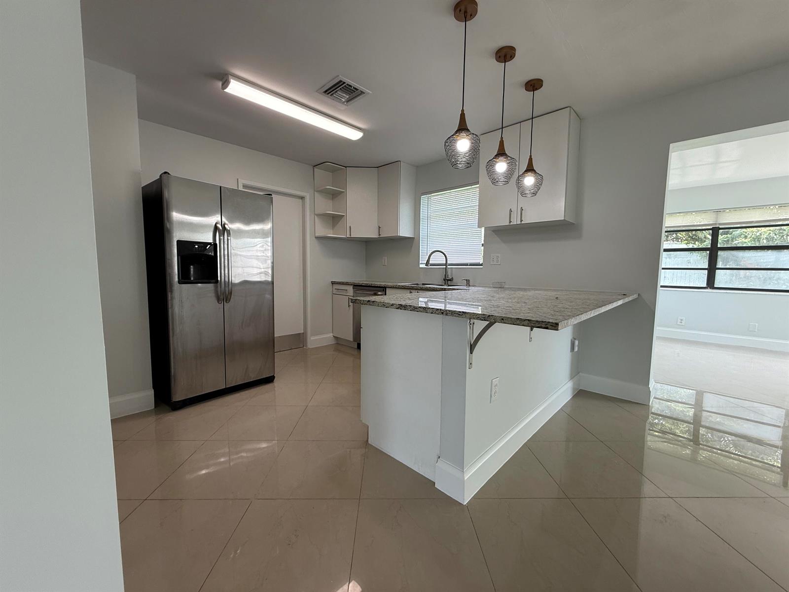A kitchen features white cabinets, granite countertops, stainless steel appliances, and tile flooring — 477 NE 35th Street, Boca Raton FL 33431, BOCA RATON, FL