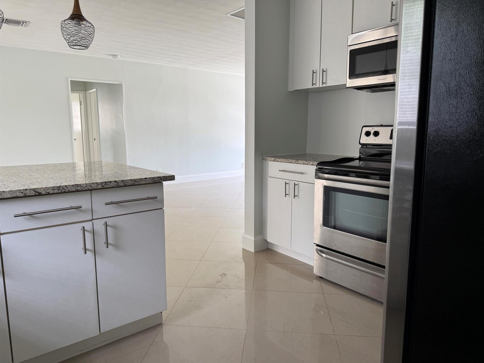 A kitchen features white cabinets, granite countertops, stainless steel appliances, and light tile flooring — 477 NE 35th Street, Boca Raton FL 33431, BOCA RATON, FL