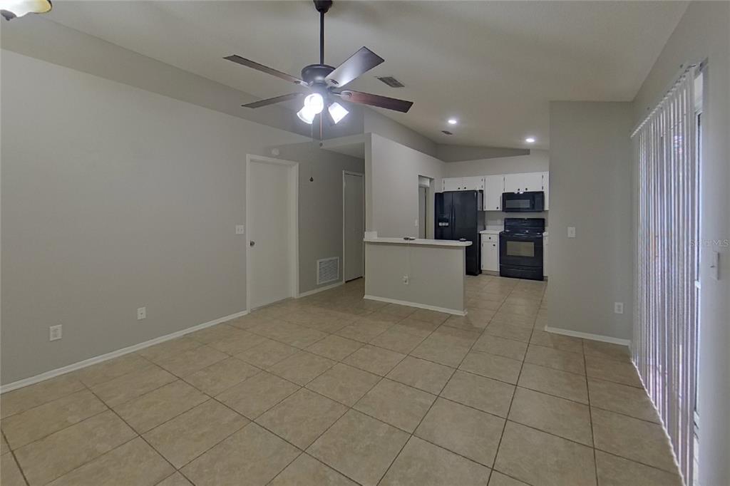 An open-concept living area with tile flooring, a ceiling fan, and an adjacent kitchen — 1248 E CLEVELAND AVENUE, APOPKA, FL