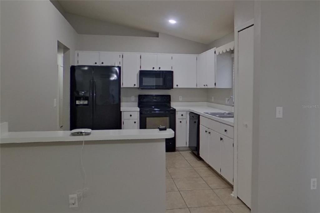 A kitchen features white cabinets, black appliances, a tile floor, and a breakfast bar — 1248 E CLEVELAND AVENUE, APOPKA, FL
