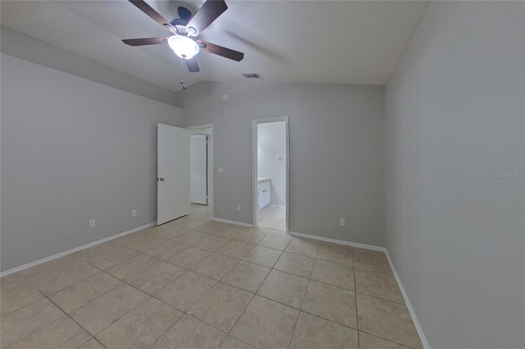 An empty room features light gray walls, tile flooring, a ceiling fan, and two doorways — 1248 E CLEVELAND AVENUE, APOPKA, FL