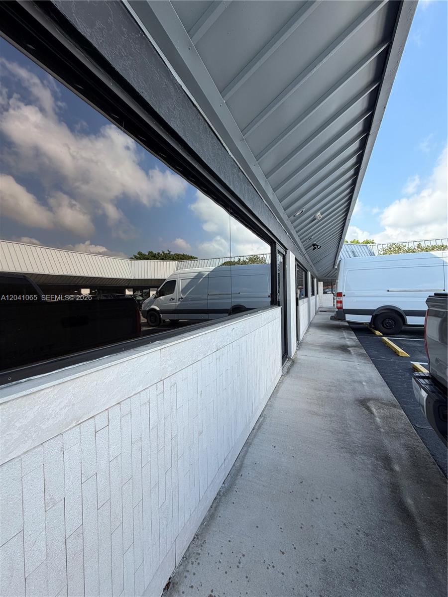 A concrete walkway runs alongside a building with a white tiled wall and windows — 10146 NW 47th St # 10146, Sunrise FL 33351, SUNRISE, FL