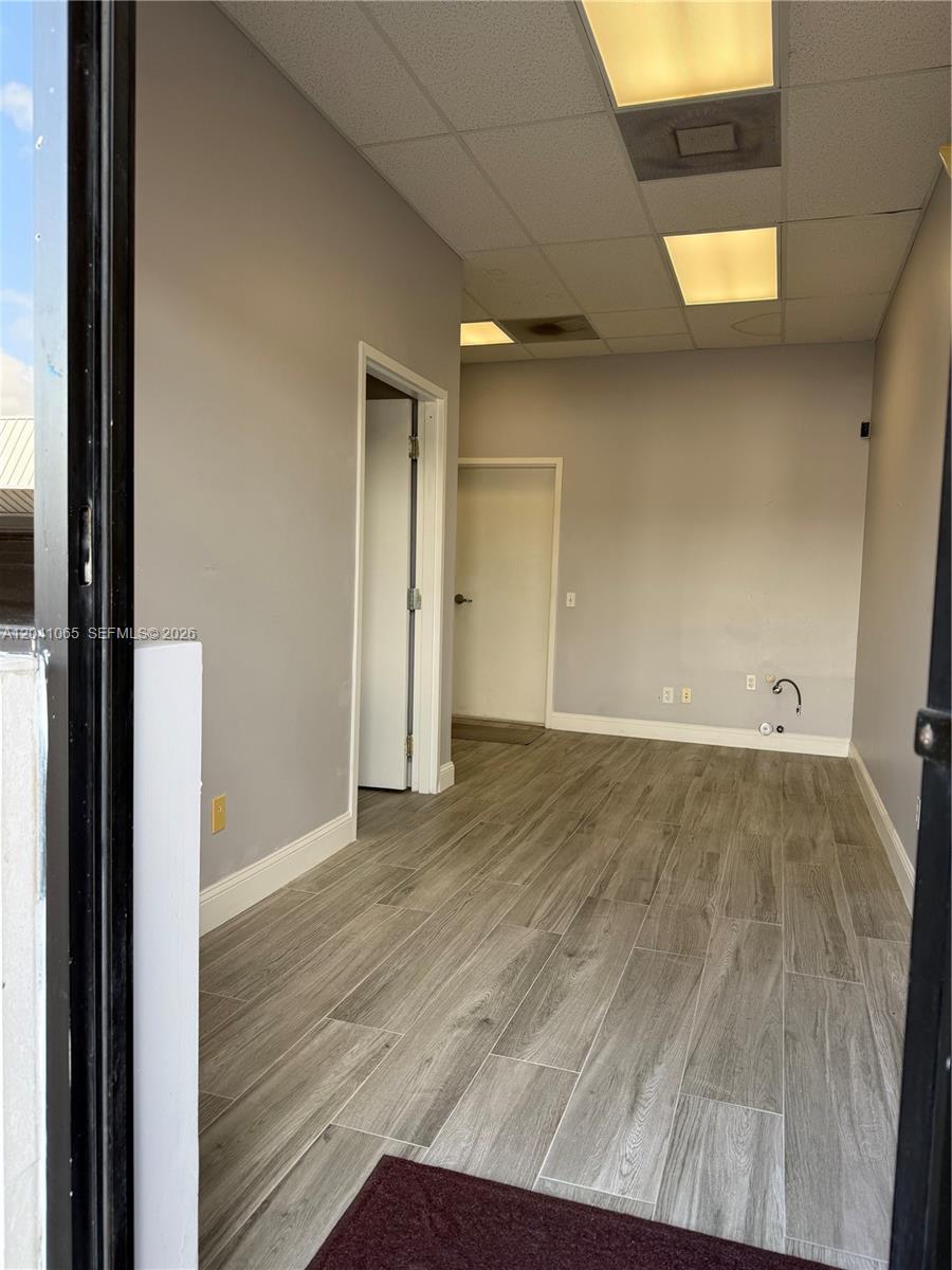 An empty office space features gray wood-look flooring, light gray walls, and recessed ceiling lights — 10146 NW 47th St # 10146, Sunrise FL 33351, SUNRISE, FL