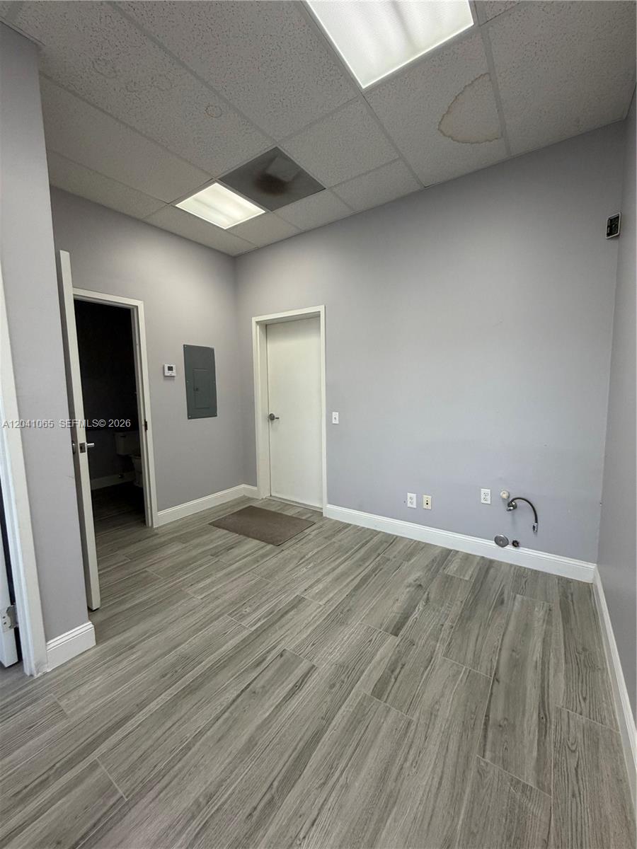 An empty office space features gray walls, wood-look tile flooring, and a small private restroom — 10146 NW 47th St # 10146, Sunrise FL 33351, SUNRISE, FL