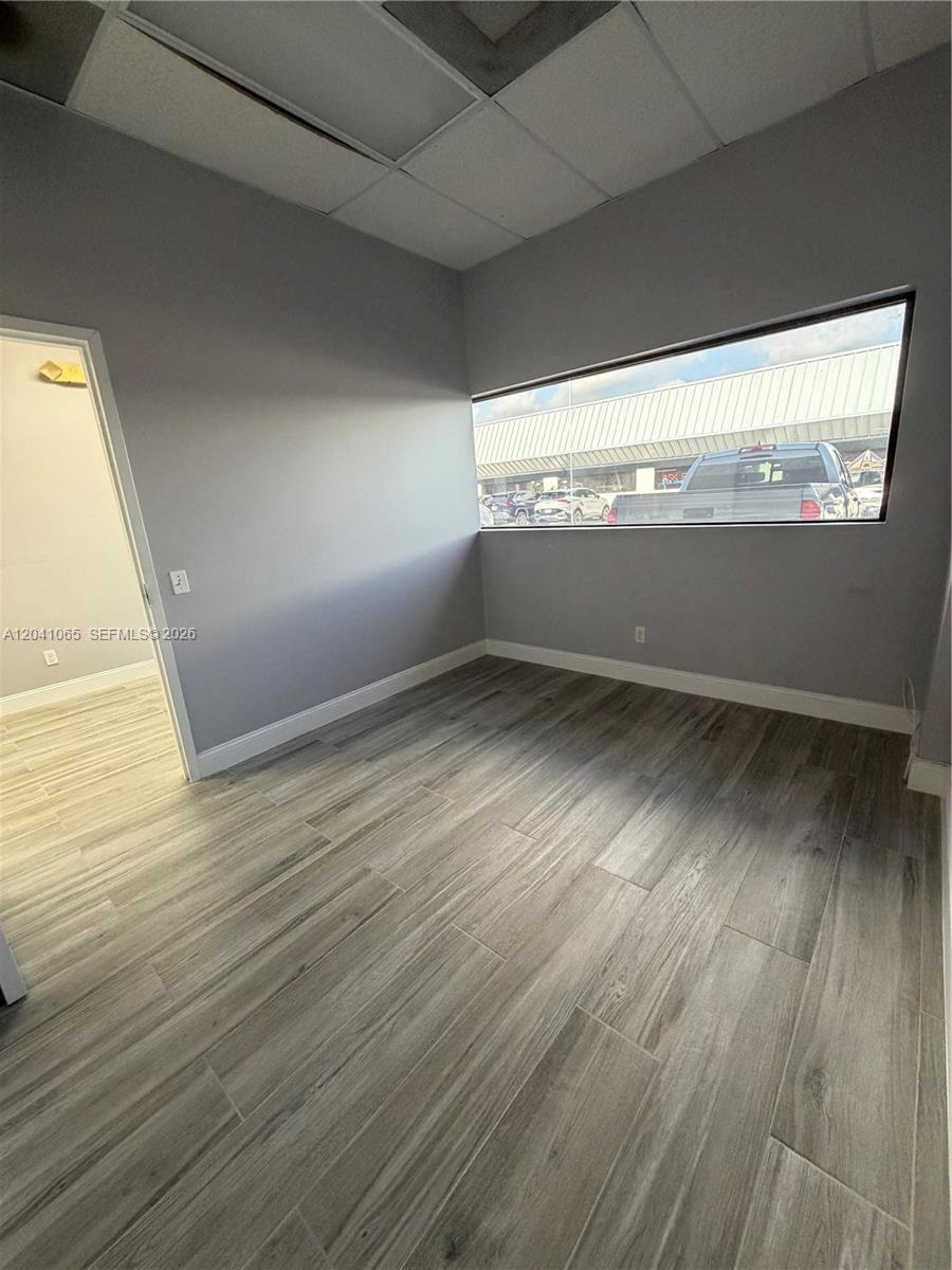 An empty office room features gray walls, wood-look tile flooring, and a horizontal window — 10146 NW 47th St # 10146, Sunrise FL 33351, SUNRISE, FL